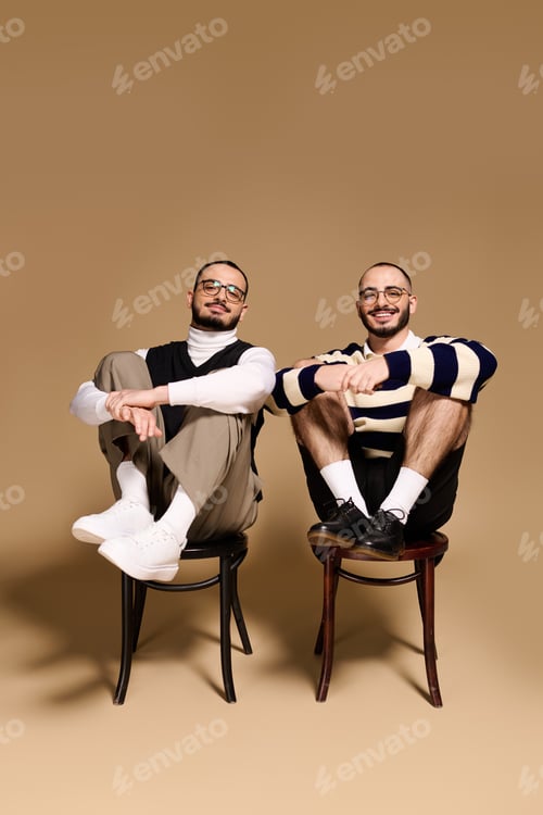 Preview: Stylish twin brothers posing together with charm and confidence in a cozy setting
