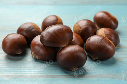 Preview: Roasted edible sweet chestnuts on light blue wooden table, closeup