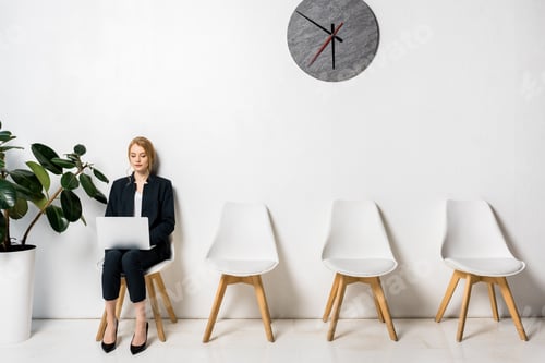 Preview: young businesswoman using laptop while sitting on chair and waiting in line