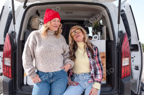 Preview: Portrait of Two smiling female friends enjoying camper van life on road trip