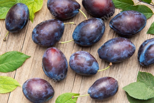 Preview: Ripe purple plums fallen on wooden table