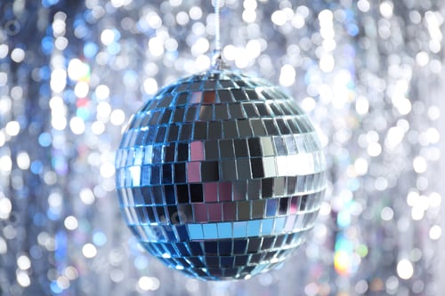 Preview: Disco ball with festive silver ribbons on background