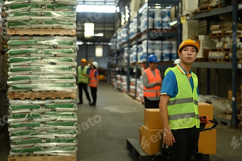 Preview: Shot of male warehouse worker in hardhats and jackets pulling a pallet truck walking.