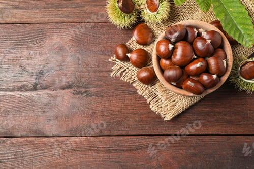 Preview: Fresh sweet edible chestnuts on brown wooden table, flat lay. Space for text
