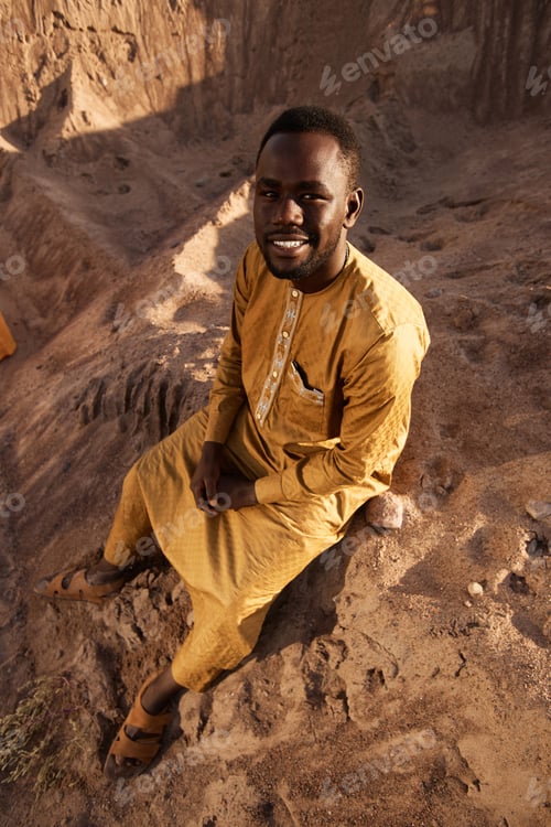 Preview: Smiling African American Man Sitting on Sand in Sunlight