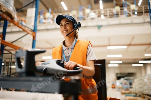Preview: Happy female warehouse worker driving pallet jack through storage compartment.