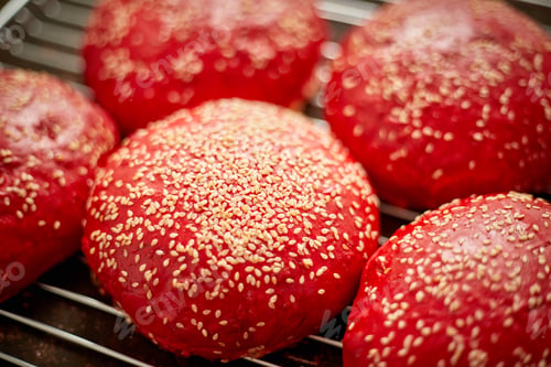 Preview: Fresh baked red homemade burger buns with sesame top view. Placed on metal grill