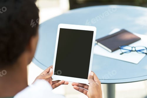 Preview: Young businessman sitting at workplace holding digital tablet with blank screen, checking mail