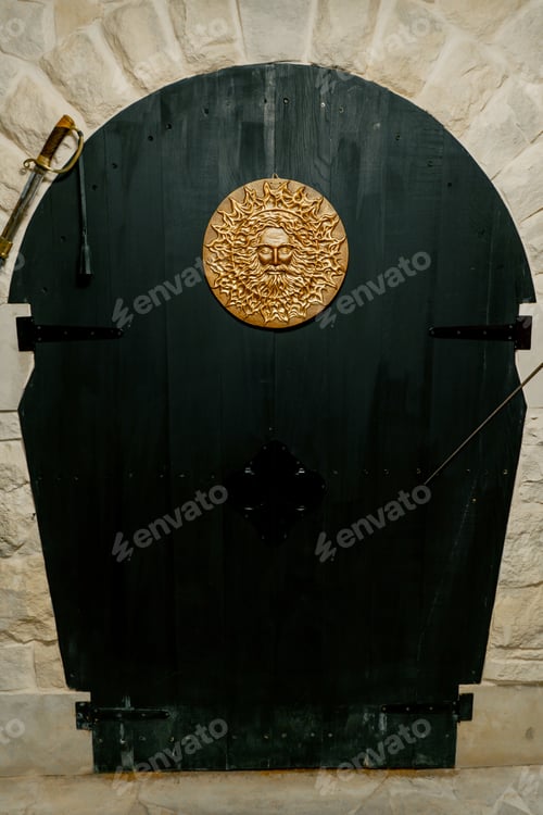 Preview: Handmade golden decoration in the form of a sun on large wooden doors at the entrance cellar