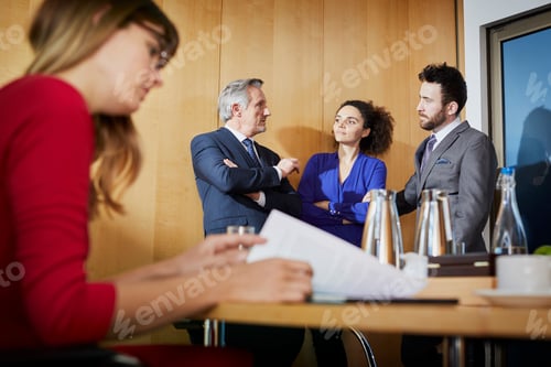 Preview: Businesswoman reading paperwork at boardroom table during meeting