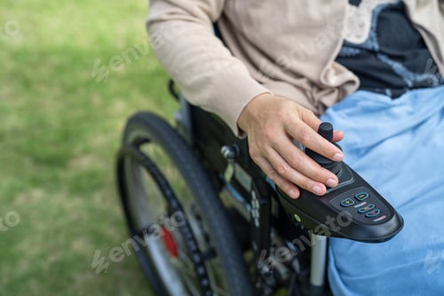 Preview: Hand on Wheelchair Joystick on Grassy Lawn