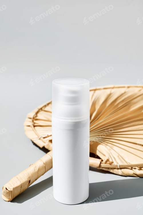 Preview: White cream tube near dried palm leaf on pastel gray background.