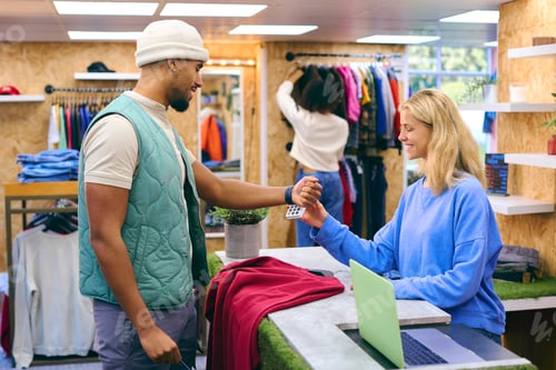 Preview: Male Customer Paying Sales Assistant In Fashion Store Making Contactless Payment With Smart Watch