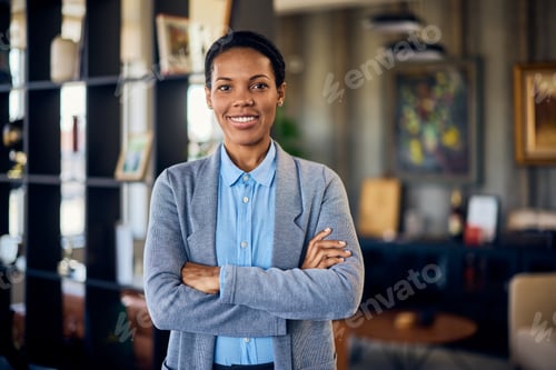 Preview: Portrait of a smiling African woman, holding her hands crossed in the office.