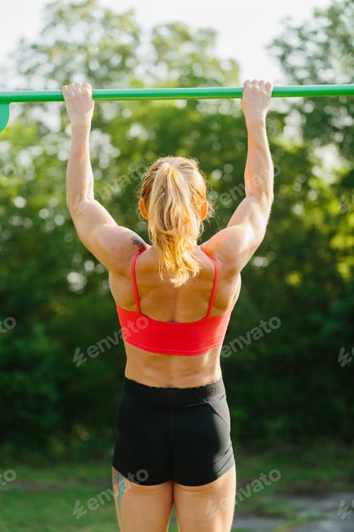 Preview: Woman exercising pulling up on outdoor bar