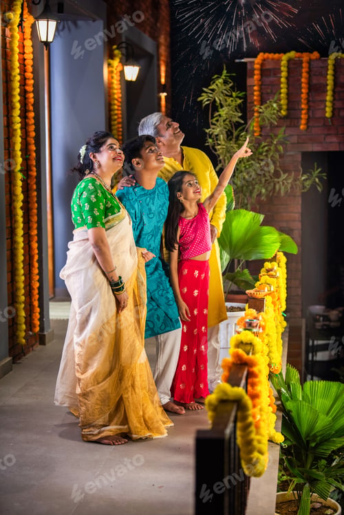 Preview: Indian family celebrating Diwali, with a young girl pointing at fireworks in the night sky