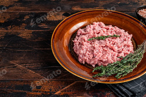 Preview: Ground chicken or turkey meat, raw Poultry on rustic plate with herbs. Dark background.