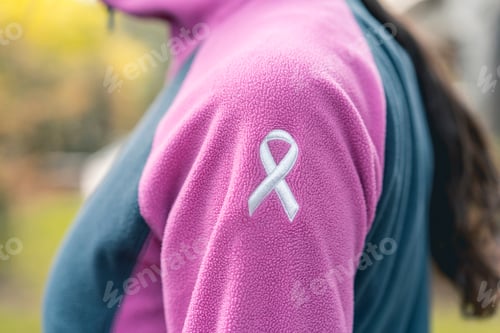 Preview: Side view of a woman wearing a sweatshirt with an embroidered cancer awarness ribbon.