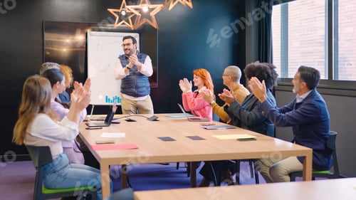 Preview: Coworkers congratulating a colleague applauding in a meeting room