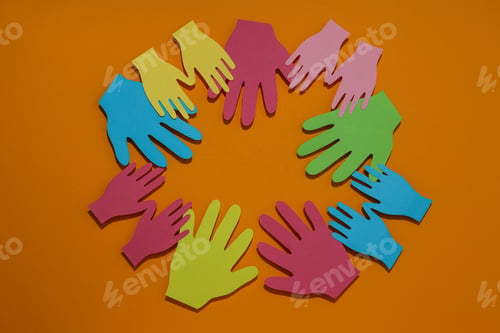 Preview: Hands are cut out of multi-colored paper on an orange background
