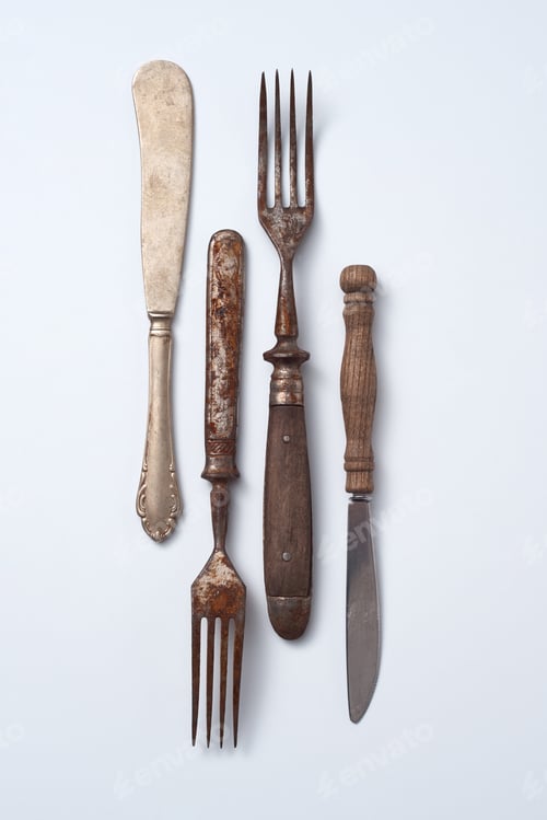 Preview: Collection of old metal with wooden handle forks and knives on a gray background with copy space