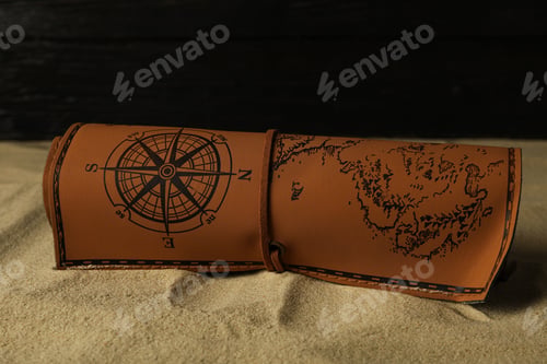 Preview: Columbus Day. A leather map lies on the sand