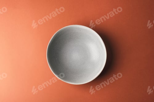 Preview: Grey plate on warm brown background. Top view, flat lay