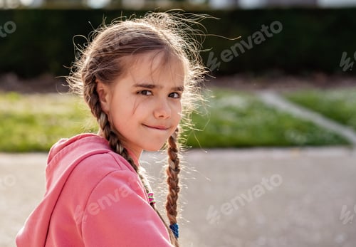 Preview: Lifestyle portrait of cute little girl with pigtails in sunlight looking at camera