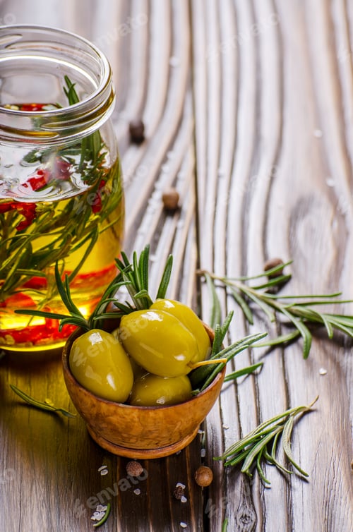 Preview: Closeup view of green olives oils and spices on kitchen table. Cooking concept