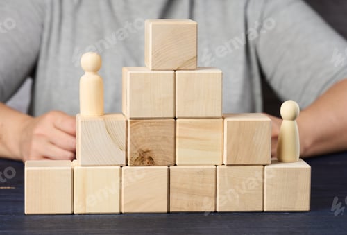 Preview: Pyramids from wooden cubes and figurines of men on the table.