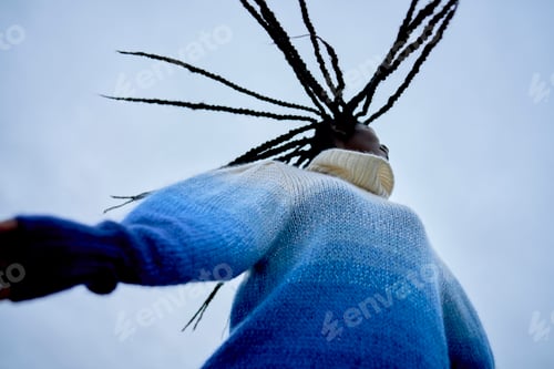 Preview: A person with braided hair reaching towards the sky