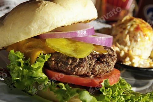 Preview: Closeup shot of a delicious and appetizing cheeseburger with tomatoes , pickles, onions and lettuce