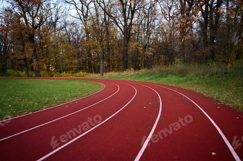 Preview: Red runninng race track with lanes at autumn park