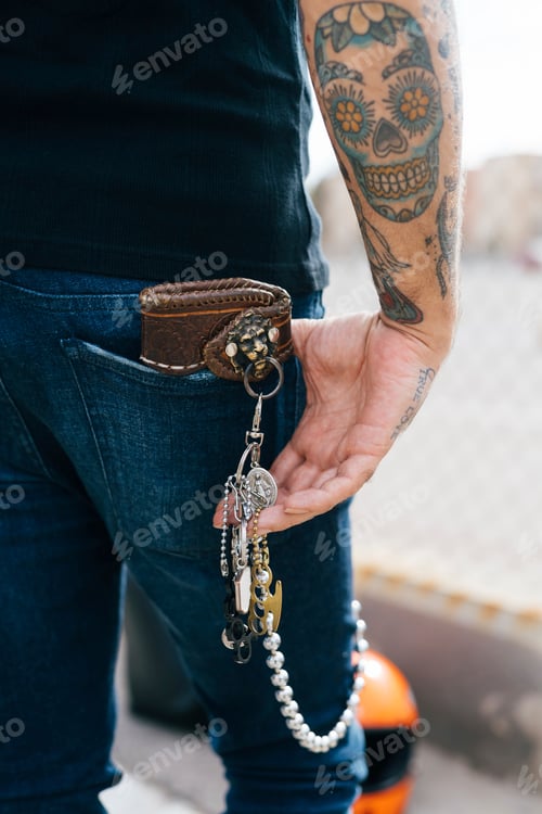 Preview: A closeup of a person's side view showcasing a tattooed arm and holding a chain of keys.