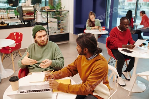 Preview: Two young intercultural businessmen in casualwear discussing financial paper