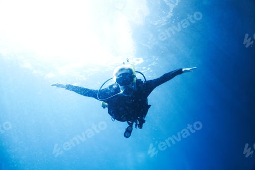 Preview: A scuba diver descending towards you with her arms wide open - Copyspace
