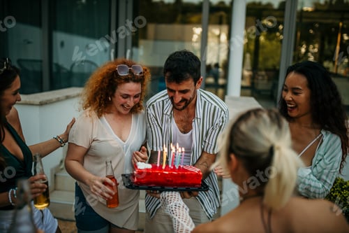 Preview: Friends celebrating birthday with cake and lit candles