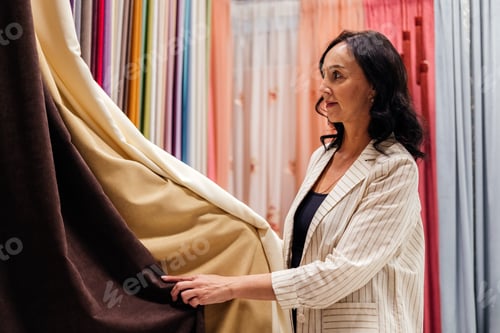 Preview: Mature woman choosing curtains in textile store indoor