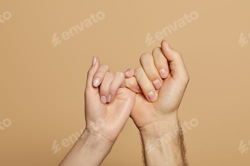 Preview: cropped view of man and woman holding little fingers isolated on beige