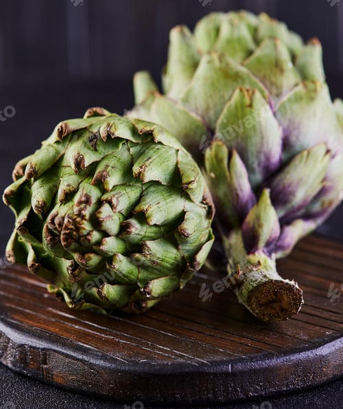 Preview: Fresh artichokes on a wooden stand against a dark background