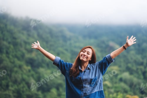 Preview: A female traveler close her eyes and open arms with a beautiful green mountains on foggy day