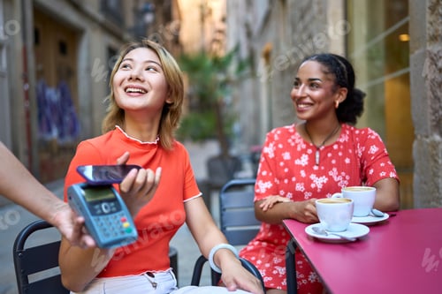 Preview: Women making contactless payment through a mobile in a cafeteria
