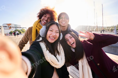 Preview: Cheerful group of friends taking a selfie outdoors in the city, smiling and looking at camera.