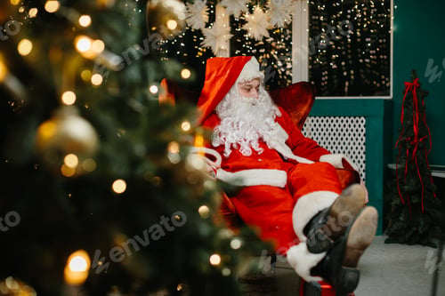 Preview: Santa claus relaxing on armchair by christmas tree