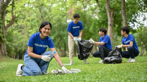 Preview: A smiling Asian female volunteer is helping her team clean up an area in a public park.