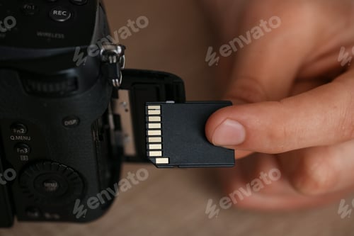 Preview: Man inserting SD memory card into photo camera, closeup