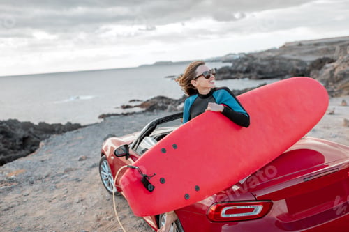 Preview: Young surfer with surfboard on the sports car on the beach