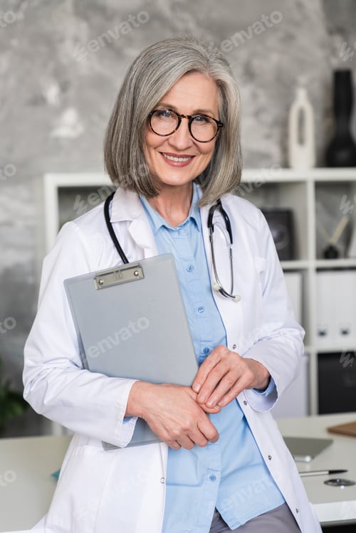 Preview: Mature female doctor in uniform, confident and trusted, smiling at camera, ready to help patients.