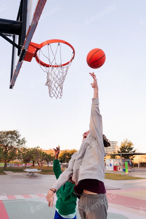 Preview: two young friends play basketball on a city court
