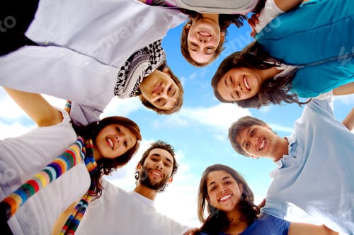 Preview: Group Of Happy Friends Smiling With Heads Together Outdoors With A Blue Sky In The Background